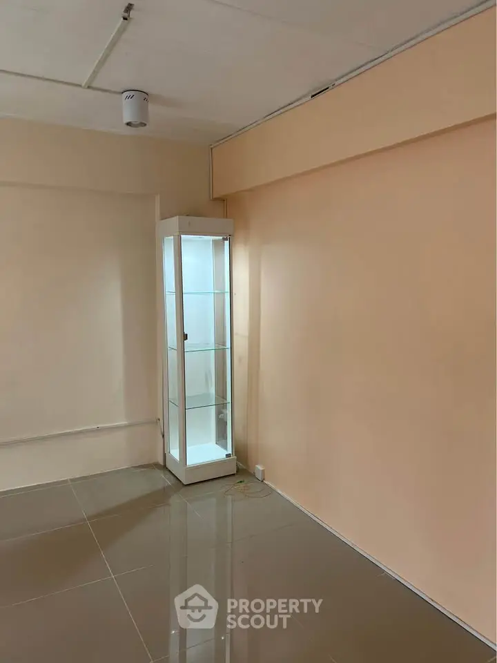 Spacious room with glossy tiled floor and a glass display cabinet, ideal for showcasing collectibles.