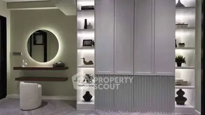 Modern interior with stylish shelving and round mirror in elegant living space.