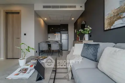 Modern living room with cozy seating and stylish decor, open layout to dining area and kitchen.