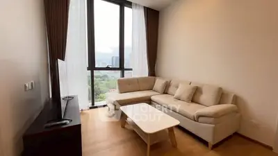 Modern living room with large windows and city view, featuring a cozy sectional sofa and sleek TV stand.