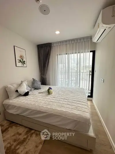 Modern bedroom with large window and stylish decor in a contemporary apartment.