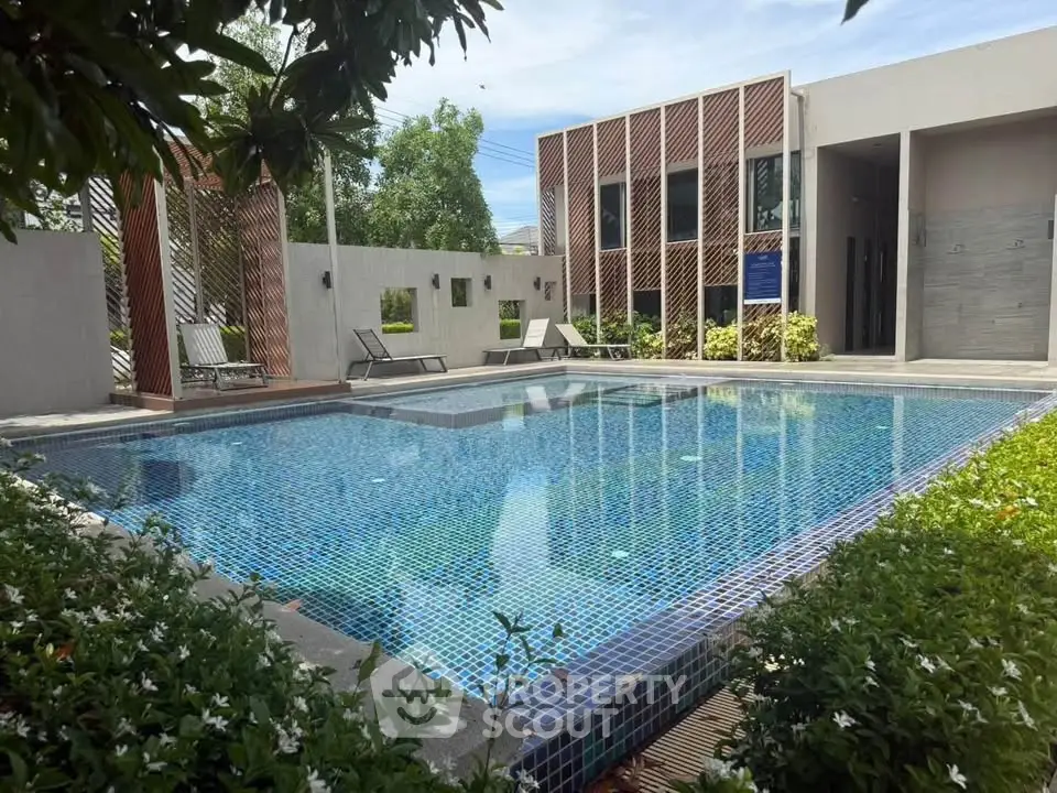 Luxurious modern pool area with stylish loungers and lush greenery, perfect for relaxation and leisure.