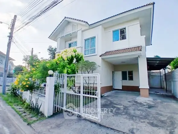 Charming two-story house with gated driveway and lush garden in a serene neighborhood.