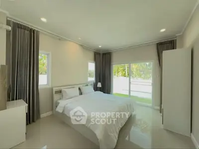 Spacious bedroom with large windows and modern decor, offering a serene and inviting atmosphere.