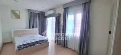 Spacious bedroom with large windows and modern decor in a bright apartment.