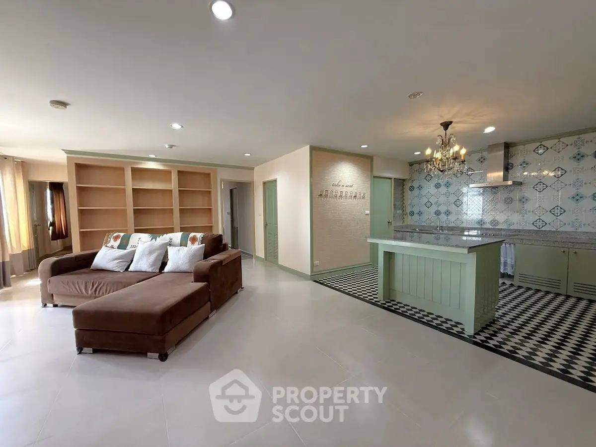 Spacious open-plan living room with modern kitchen and elegant chandelier