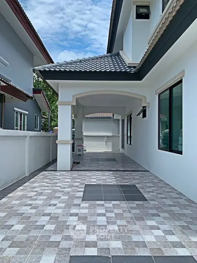 Modern house exterior with tiled pathway and covered entrance, showcasing contemporary architecture.