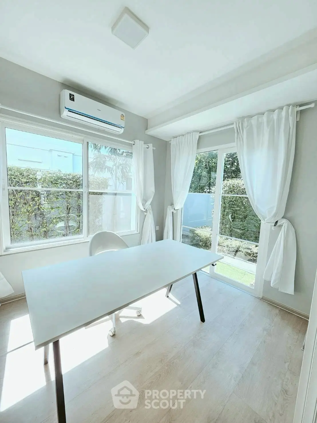 Bright study room with large windows and garden view, featuring modern minimalist decor.