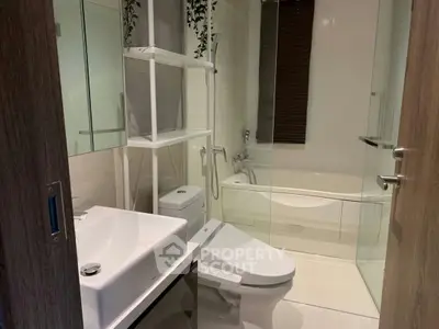 Modern bathroom with sleek fixtures and a glass-enclosed bathtub, offering a clean and contemporary design.