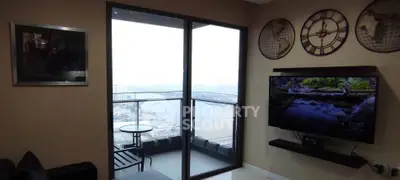 Modern living room with balcony view and wall-mounted TV, featuring stylish decor and cityscape backdrop.
