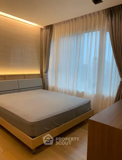 Modern bedroom with large window and stylish curtains in a high-rise apartment.
