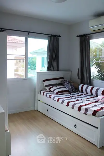 Cozy bedroom with striped bedding and large windows offering natural light