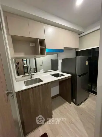 Modern compact kitchen with sleek cabinetry and stainless steel appliances in a stylish apartment.