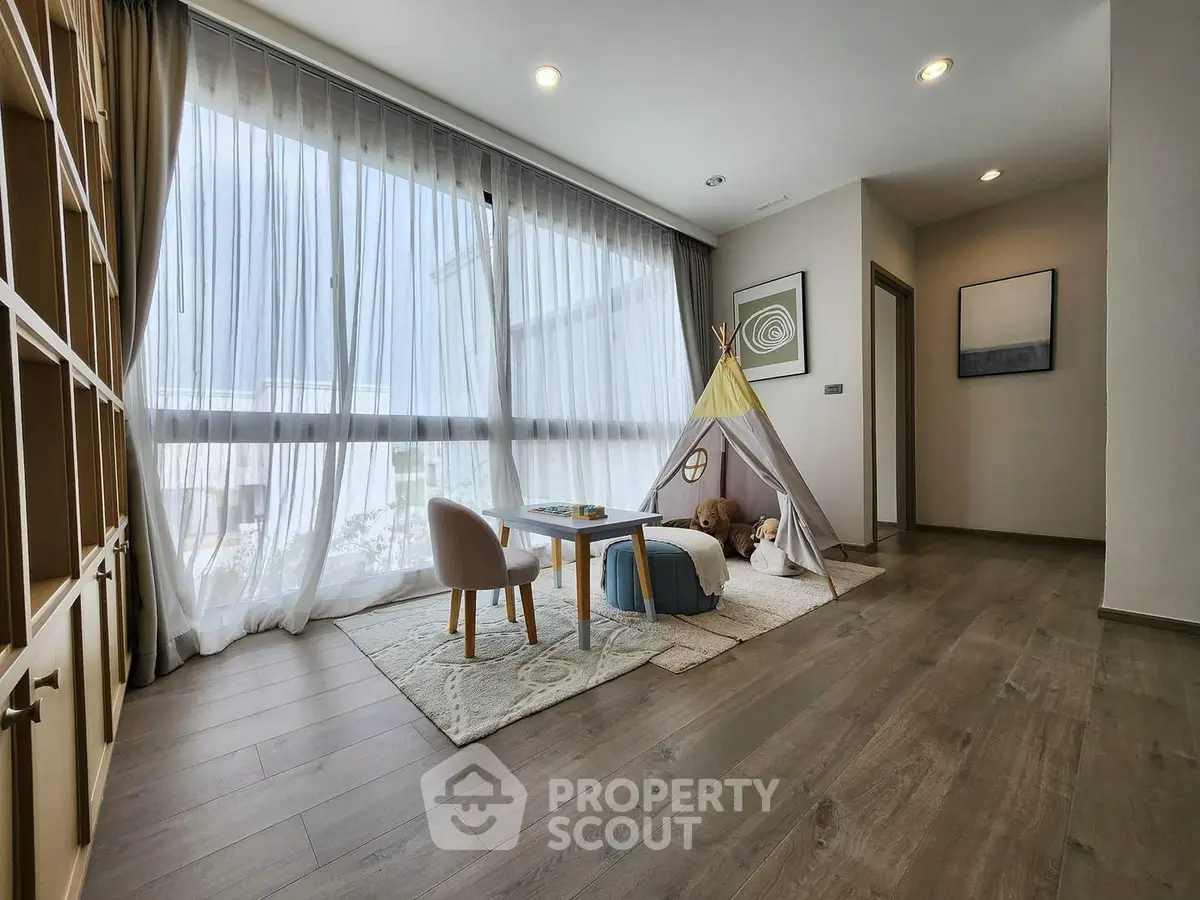 Spacious modern living room with large windows and children's play area, featuring elegant wooden flooring.