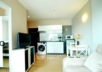 Modern open-plan living room with kitchen, featuring washing machine and cozy dining area.