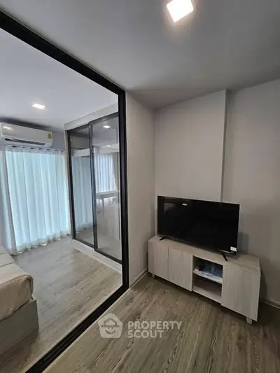 Modern bedroom with sleek TV setup and large mirrored wardrobe in a stylish apartment.