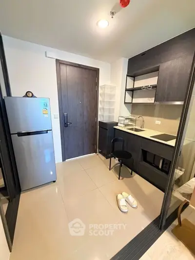 Modern compact kitchen with sleek cabinetry and appliances in a stylish apartment.