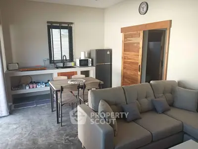 Modern open-plan living room with cozy sofa and dining area, featuring a sleek kitchen with appliances.