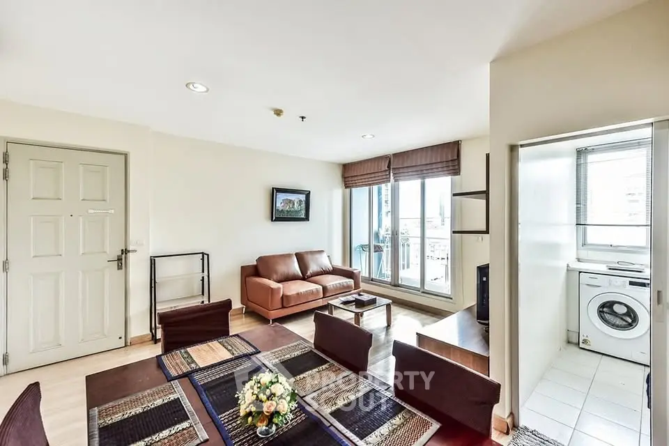 Spacious living room with modern decor and natural light, featuring a cozy seating area and a washing machine nook.