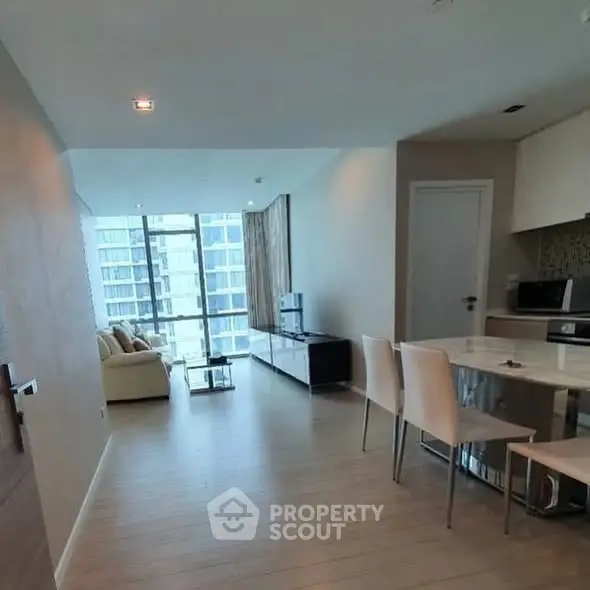 Modern open-plan living room with dining area and large windows in a high-rise apartment.