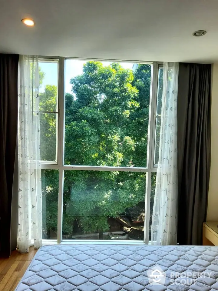 Bright bedroom with large window and lush green view