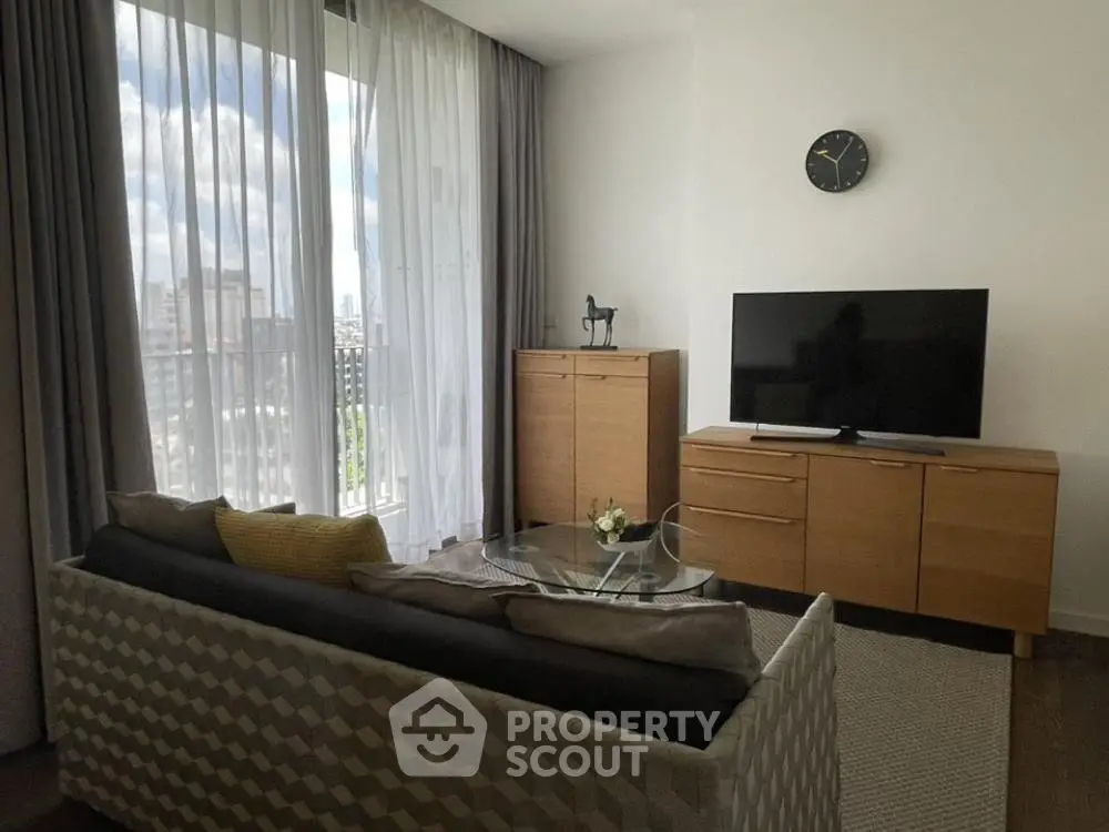 Modern living room with stylish furniture and city view through large window.