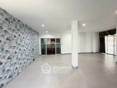 Spacious open-plan living area with unique wallpaper and modern kitchen.