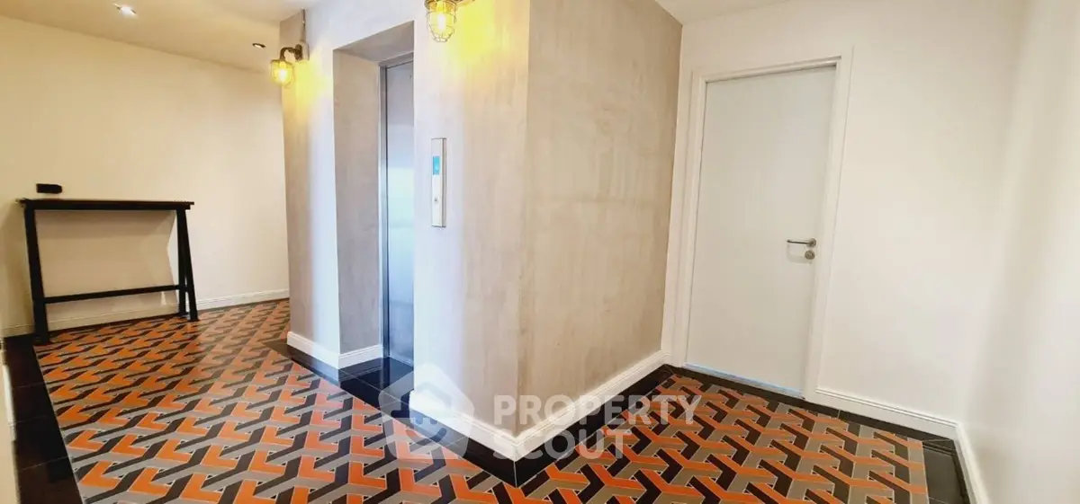 Stylish modern building corridor with unique geometric floor tiles and elevator access.
