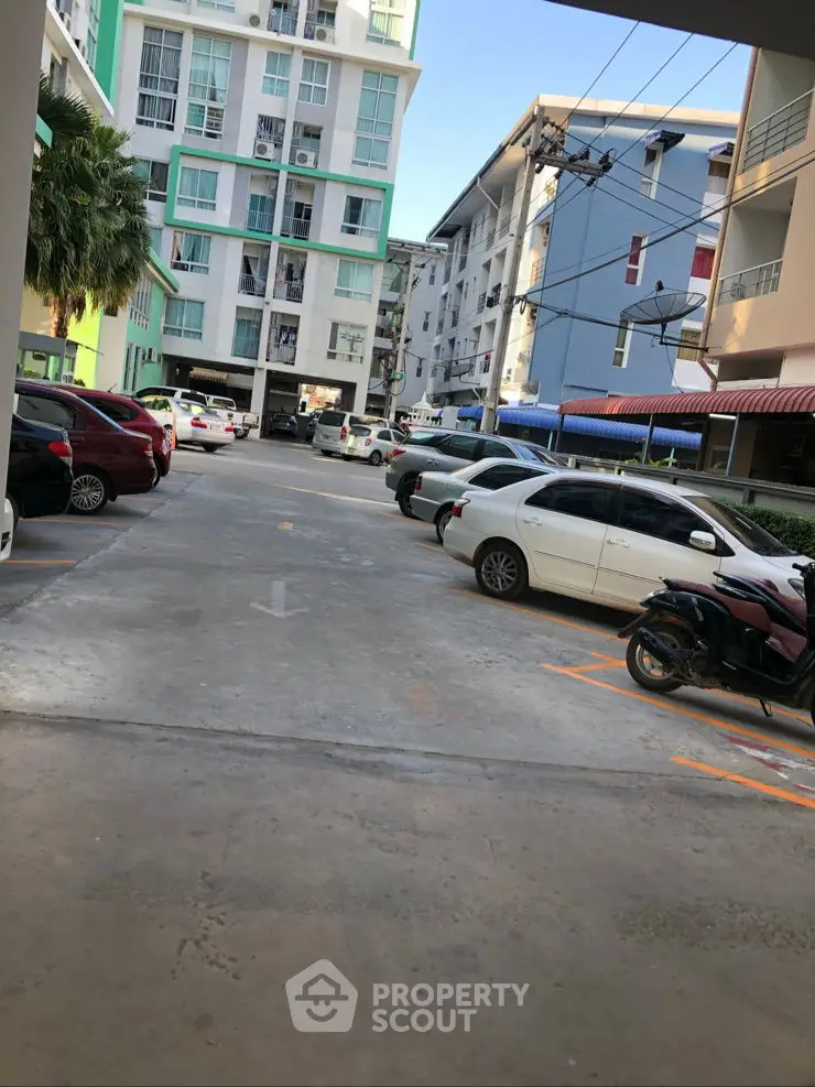 Modern apartment building with spacious parking area and multiple vehicles.