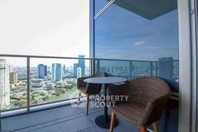 Stunning city view from modern high-rise balcony with cozy seating.