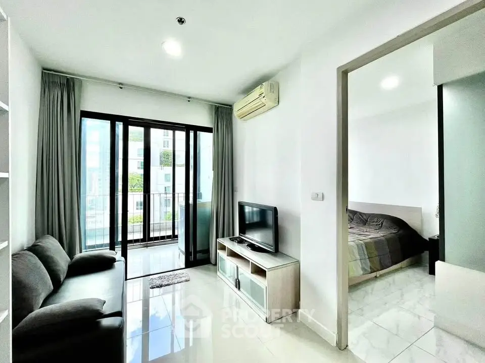 Modern apartment with open living room and bedroom, featuring sleek design and natural light.