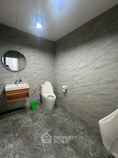 Modern bathroom with sleek grey tiles and round mirror