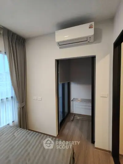 Modern bedroom with air conditioning and natural light, featuring a sleek design and neutral tones.