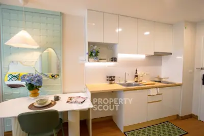 Modern kitchen with sleek white cabinets and cozy dining area in stylish apartment.