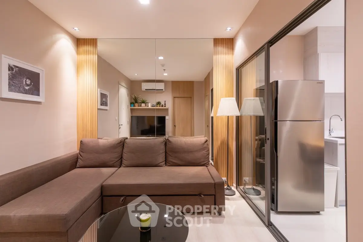 Modern living room with sleek design and stainless steel fridge in open layout.