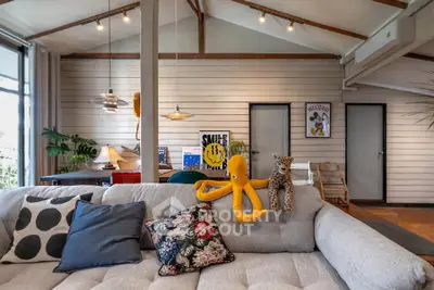 Charming living room with vaulted ceilings and cozy decor, featuring plush sofa and stylish lighting.