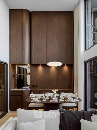 Luxurious modern dining area with high ceilings and elegant wooden cabinetry, perfect for sophisticated gatherings.