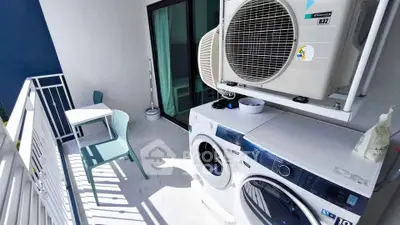 Modern balcony with laundry appliances and seating area in a stylish apartment.