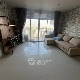 Spacious living room with modern decor and large windows leading to a balcony.