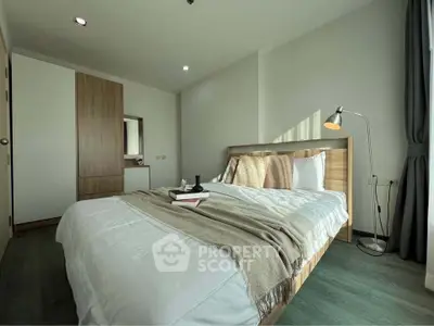 Modern bedroom with cozy bed, stylish lamp, and wooden wardrobe in a bright apartment.