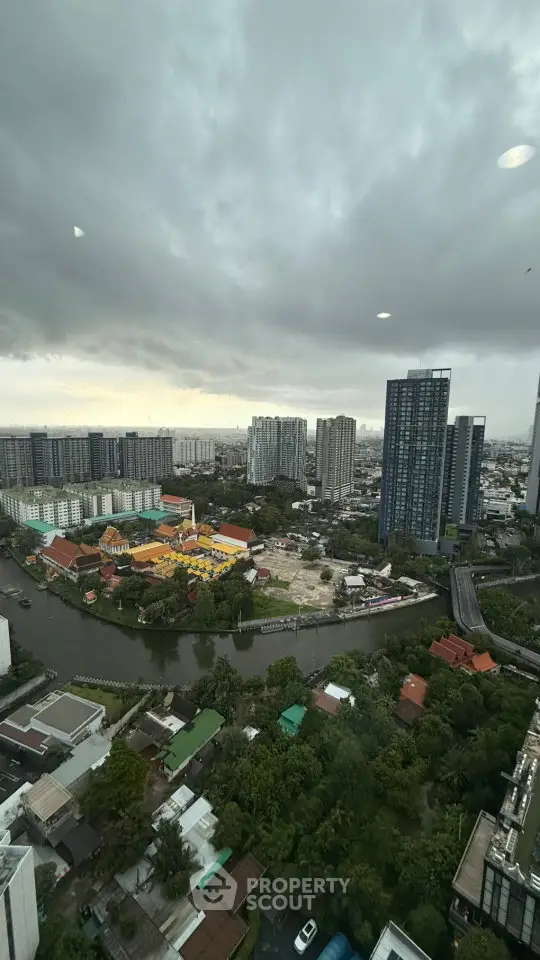 Stunning cityscape view from high-rise building with river and modern skyscrapers under cloudy sky.