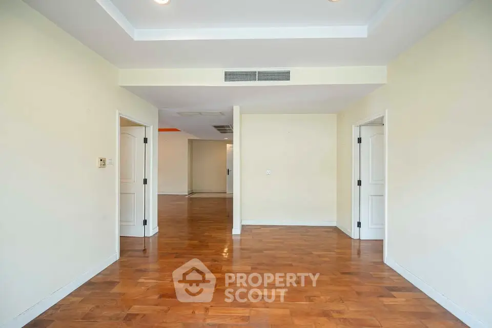 Spacious empty room with wooden flooring and recessed lighting, ideal for customization.