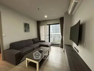 Modern living room with large sofa, flat-screen TV, and city view balcony.