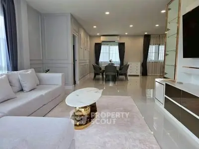 Spacious modern living room with elegant decor and open dining area, featuring a luxurious white sofa and marble coffee table.