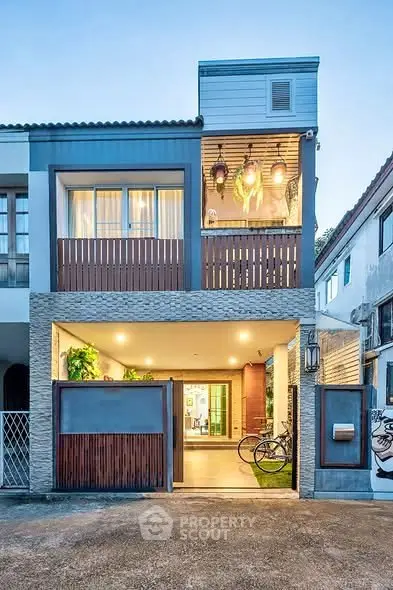 Modern townhouse with stylish facade and warm lighting, featuring a cozy balcony and spacious garage.