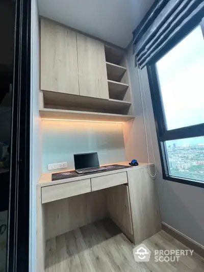 Modern study nook with built-in desk and shelves, offering a city view through large window.