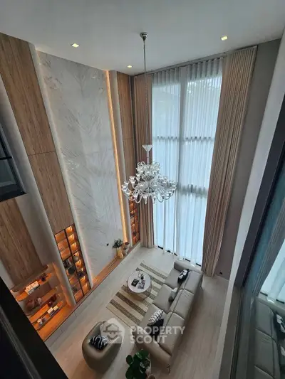 Luxurious high-ceiling living room with elegant chandelier and floor-to-ceiling windows.