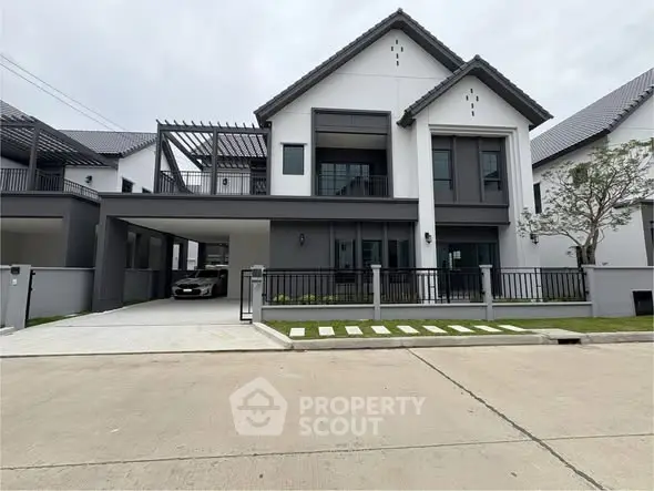 Modern two-story house with sleek design and spacious driveway in a suburban neighborhood.