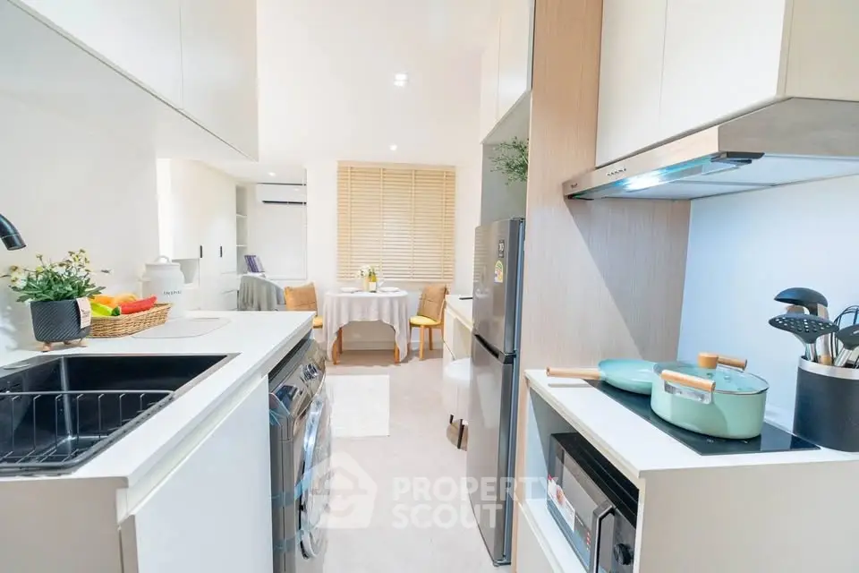 Modern kitchen with sleek appliances and cozy dining area in a bright, open layout apartment.