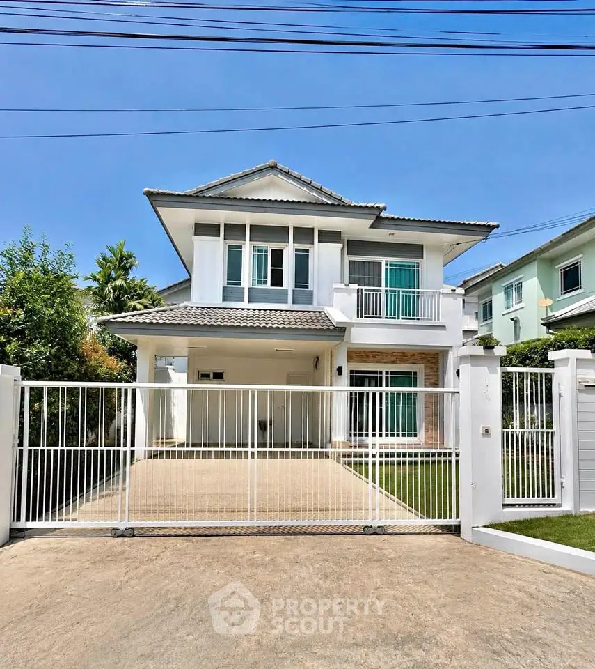 Charming two-story house with gated driveway and lush greenery, perfect for family living.